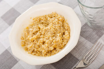 Boiled oatmeal porridge served in white plate. Concept of diet food