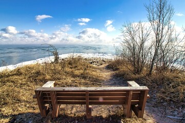 An empty bench faces a cloud shrouded Lake Michigan from a point along the frozen shoreline on a...