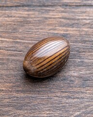 Close-up of a striped, oval-shaped seed on a wooden surface