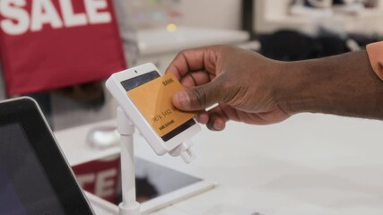 Close-up of hand of unrecognizable man paying by contactless credit card in shop, copy space