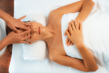 Panorama top view of woman enjoying relaxing anti-stress head massage and pampering facial beauty skin recreation leisure in dayspa modern light ambient at luxury resort or hotel spa salon. Quiescent