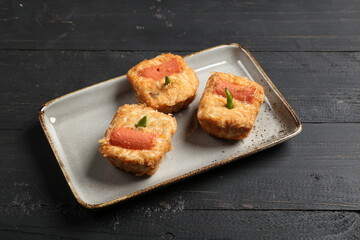 Close-up of traditional Indonesian fried stuffed tofu (Tahu Fantasi) served on a ceramic plate over a dark wooden background.