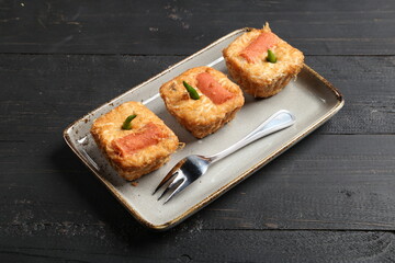 Close-up of traditional Indonesian fried stuffed tofu (Tahu Fantasi) served on a ceramic plate over a dark wooden background.