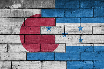 colourful painted big flag of japan and flag of honduras on a massive old brick wall background....