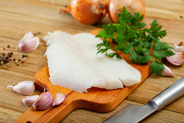 Raw Atlantic halibut fillet on wooden table with condiments. Seafood delicacy