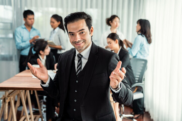 Obraz premium Portrait of happy businessman looking at camera with motion blur background of business people movement in dynamic business meeting. Habiliment