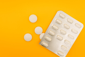 Blister pack and scattered pills on a yellow background