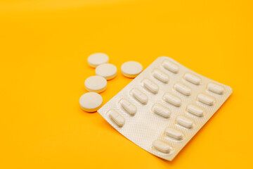 Blister pack and scattered pills on a yellow background