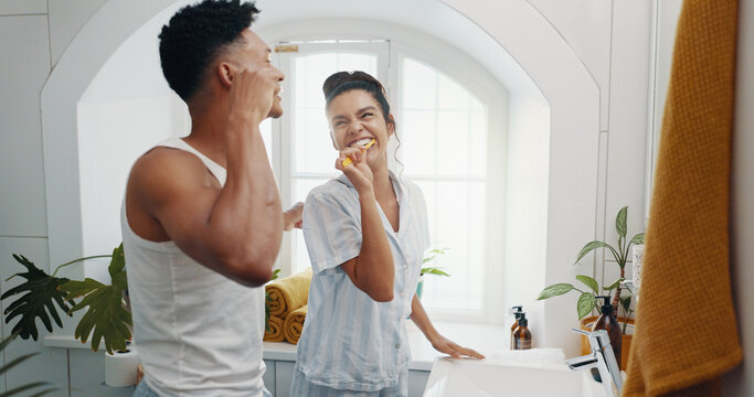 Brushing teeth, laughing and morning with couple in bathroom for dental hygiene or oral care. Happy, love and mirror with funny people in home together to prevent cavity or gum disease for health
