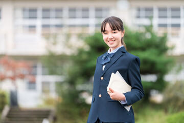 学校の校舎の前に立つ制服姿の中学生・高校生・小学生
