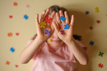 A child hides face behind his hands with colorful puzzles - the emblem of autism. Mental and developmental disorders in people with autism spectrum disorder