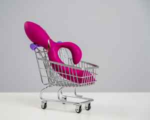 Sex toy in miniature shopping cart on white background. 