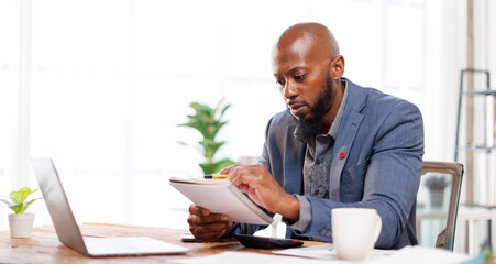 Fototapeta premium An office scene showing a professional at his desk, using a laptop for various business activities and strategies.African American Businessman work.