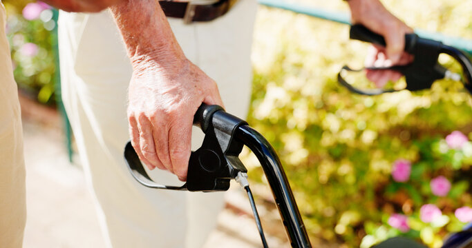 Walker, hands and medical with old man outdoors for rehabilitation, support and osteoarthritis. Healthcare, walking and retirement with closeup of senior person with a disability in nursing home