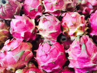 Dragon fruit, or pitaya, is stored in containers at the market stall. Dragon fruit is the fruit of...