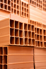 Close-up of a pile of orange clay hollow block laying on top of each other. Construction building material.