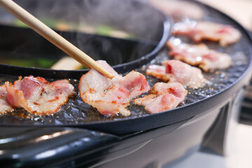 Party for barbecue japanese style, yakiniku. Meats are being cooked on stove frying pan