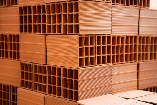 Background of orange clay hollow blocks stacked in a neat arrangement. Construction materials factory.
