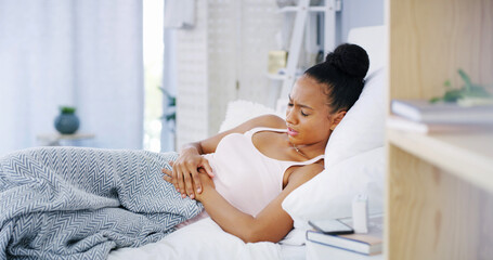 Period, woman and stomach pain on bed in home with endometriosis, menstruation cramps or...