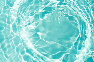 Blue water with ripples on the surface. Defocus blurred transparent blue colored clear calm water surface texture with splashes and bubbles. Water waves with shining pattern texture background.