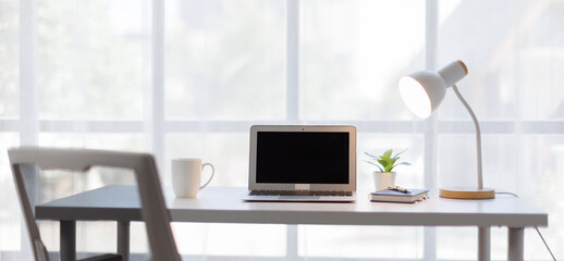 Screen laptop computer mockup a large open plan office space after working hours and accessories on...