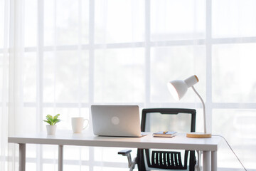 Laptop Computer, notebook, office space ,and eyeglasses sitting on a desk in a large open plan office space after working hours	