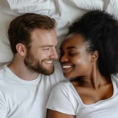 Obraz premium Mixed couple, black woman and white man smiling at each other in bed. Square photography