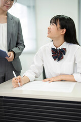 授業中に先生を見ている高校の制服を着たアジアの 10 代の少女