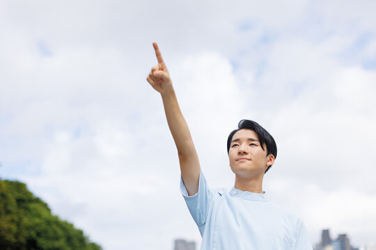 ナース服を着たアジアの 10 代の少年が前を向いて指差す