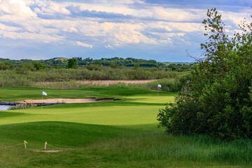 Obraz premium A golf course with a green grassy field and a pond