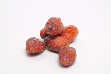 Close up of a pile of ripe brown dates isolated on a white background.Fruit typical of the Arab region. Sweet and legit taste.Copy space for text.For graphic design or banner background
