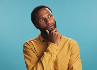 Black man, thinking and worker for choice in studio, job opportunity and blue background. Male...