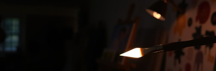 Naklejka premium Softly glowing paint brush in a dimly lit art studio, colorful objects, art studio, painting supplies