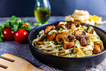 A delicious serving of creamy tagliatelle pasta topped with golden chicken and sautéed mushrooms,...