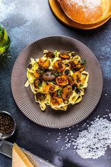 Creamy tagliatelle pasta topped with sautéed shrimp, mushrooms, and black olives, garnished with fresh herbs and Parmesan cheese.