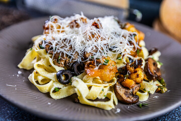 Creamy tagliatelle pasta topped with saut&eacute;ed shrimp, mushrooms, and black olives, garnished with fresh herbs and Parmesan cheese.