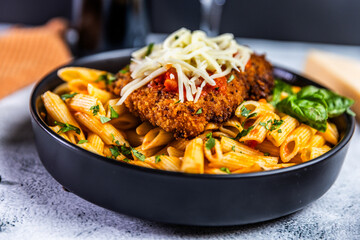Crispy breaded chicken served over penne pasta tossed in a spicy arrabbiata sauce, topped with fresh basil and shredded mozzarella cheese.