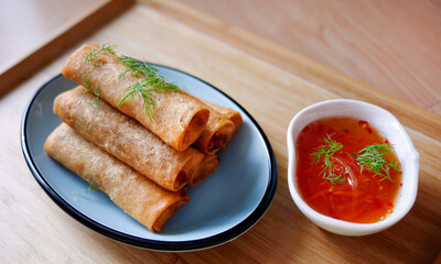 Deep fried spring roll in golden brown color, served in a blue oval shape plate, famous local street food in Thailand, food industry concept