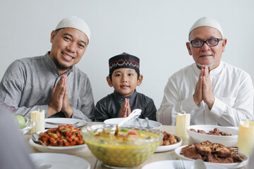 Portrait Of Multi Generation Muslim Family Showing Gesture Apologize At Dining Room Celebrating Eid Mubarak