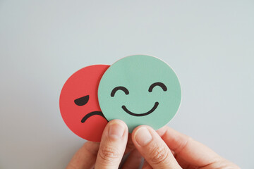 Hands holding sad face hiding behind happy face, bipolar and depression, mental health, split...