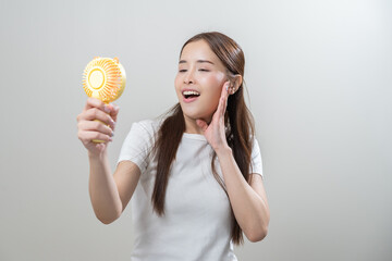 Happy summer heat wave stroke, hot weather, tired asian young woman sweaty and thirsty, refreshing with hand in blowing, wave fan to ventilation when temperature high, isolated on background.