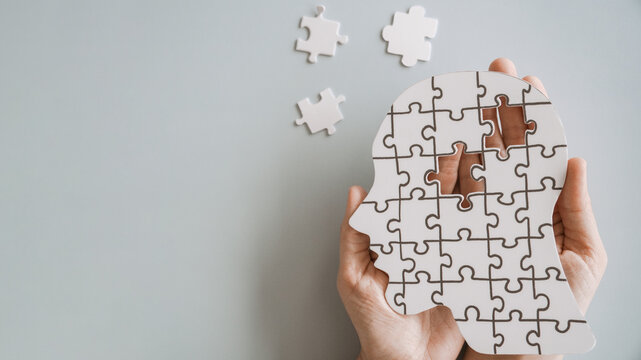 Hands holding brain with puzzle paper cutout, autism, dementia, Epilepsy and Alzheimer awareness, seizure disorder, world mental health day concept.