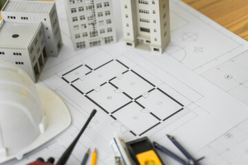 Close-up of a table with a blueprint, architect&rsquo;s tools, and an engineer&rsquo;s hat, representing building and condo design, construction planning, and structural engineering with precision and accuracy
