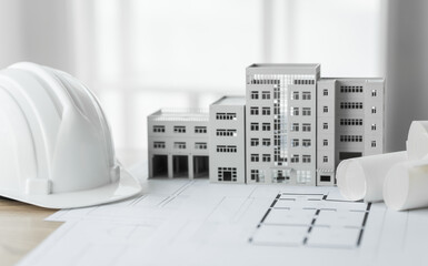 Close-up of a table with a blueprint, architect’s tools, and an engineer’s hat, representing...