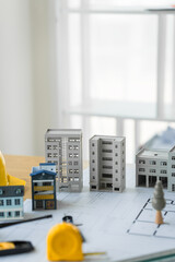 Close-up of a table with a blueprint, architect’s tools, and an engineer’s hat, representing...