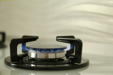 Gas burner of modern stove with burning blue flame, closeup