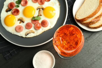 Tasty brunch. Delicious fried eggs with sausage and mushrooms served on black table, flat lay
