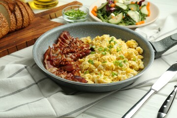 Tasty brunch. Delicious scrambled eggs, bacon and salad served on white wooden table, closeup