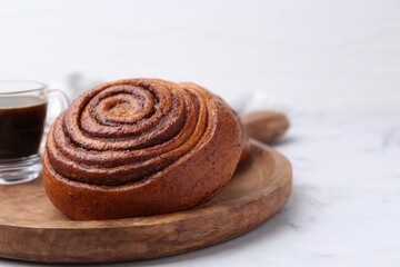 Delicious cinnamon roll on white marble table, closeup. Space for text