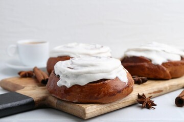 Tasty cinnamon rolls with cream and spices on white table, closeup